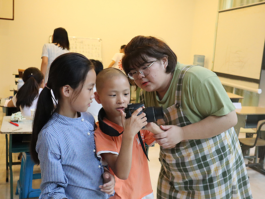 图为志愿者教授孩子们拍照技巧。四川文化网通讯员 吕秀红 摄