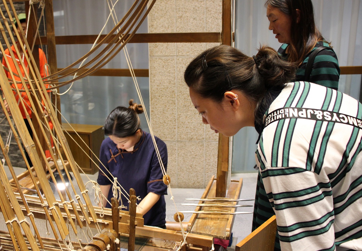 讲解员介绍提花织机的运作，团队成员们观看绣工的实际织造过程。 四川文化网通讯员 陈晓晖 摄