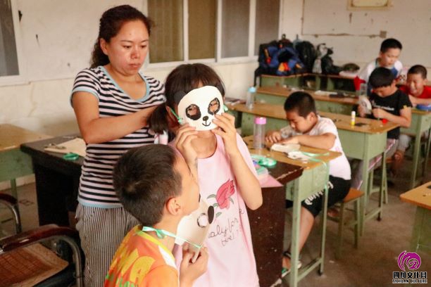 卓锦工作人员为孩子们佩戴熊猫面具。中国青年网通讯员 杨佳龙.jpeg